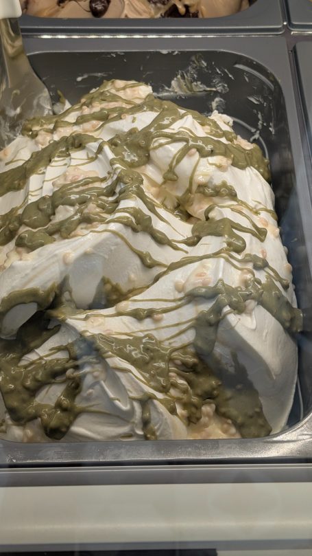 Helado de leche con chocolate blanco von veteado de pistacho y arroz crujiente.